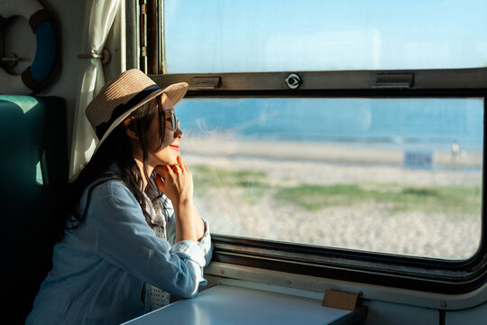 Female tourists are relaxing and watching the view while traveling by train during her summer vacation