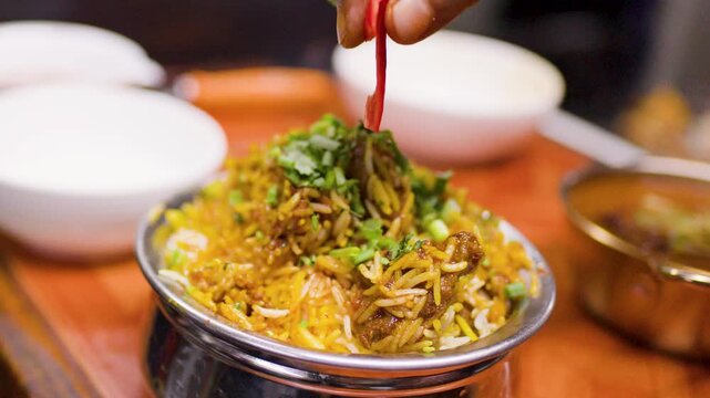 Chef Garnishing Traditional Indian Biryani Rice Dish in Restaurant Kitchen