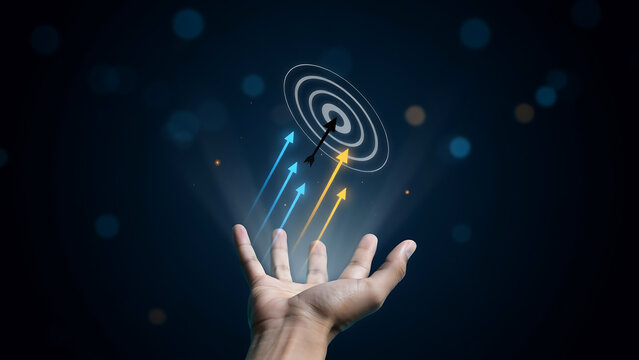 Hand releasing digital target with colorful arrows pointing upward against dark background