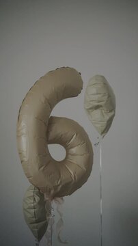 Vertical shot of beige number 6 foil balloon with heart balloon decoration for birthday party.