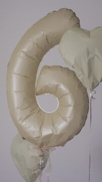 Vertical shot of beige number 6 foil balloon with heart balloon decoration for birthday party.