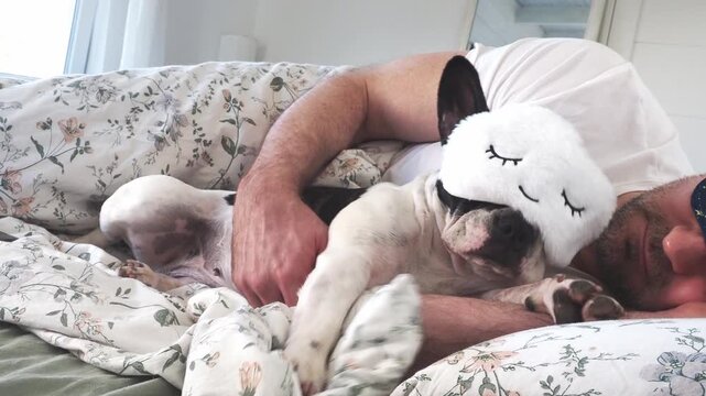 Man and charming French Bulldog sleeping in bed wearing sleep masks. Daytime sleep. Pet care, comfort, and love. Symbolizes deep bond and caring for animals. Ideal for pet lifestyle content