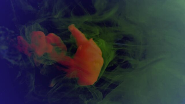 Vibrant red and yellow ink swirling in crystal clear water creating mesmerizing abstract fluid art video footage showcasing dynamic motion and organic shapes within a dark background setting