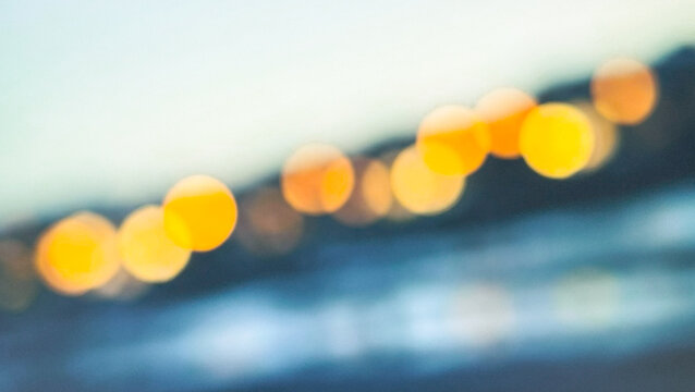 A dreamy, abstract photograph featuring blurred circles of light, resembling bokeh effects at a twilight beach scene. The soft colors create a serene atmosphere.