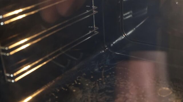 Stockholm, Sweden A woman performs a deep clean on an oven and stovetop. 