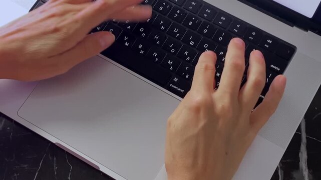 Hands swiping and typing on laptop, close-up top view showing trackpad gestures and keyboard input, suitable for computer navigation, online work, data entry, productivity and digital communication