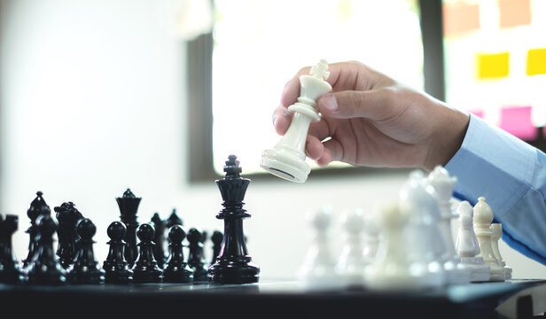Hand of business moving white king chess piece on chessboard for business strategy leadership competition and management success concept