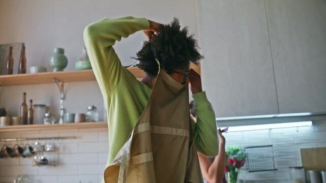 Man taking off apron kitchen dancing. Girlfriend embracing partner home cooking.