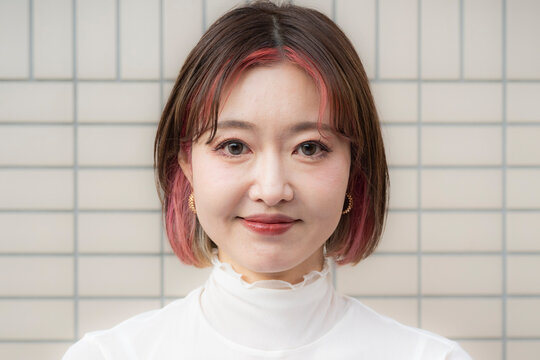 Portrait of a smiling woman against a modern tile wall background.