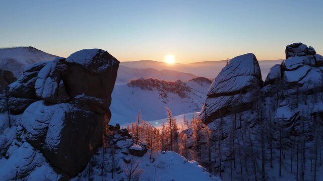 Aerial View of Sunrise Through Snowy Rocks and Trees in Winter Mongolia (겨울 몽골의 눈 덮인 바위와 나무들 사이로 떠오르는 일출의 드론 항공 뷰)