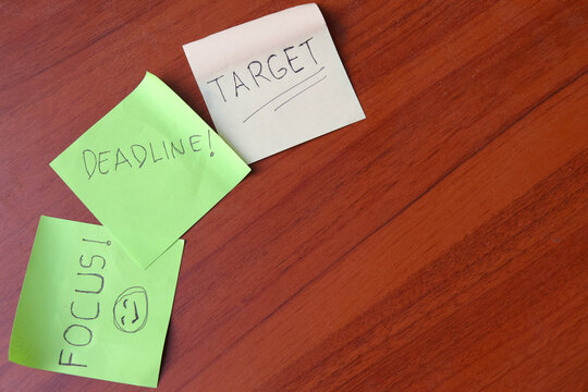 Top view of colorful sticky notes with handwritten words deadline target and focus on wooden desk with copy space