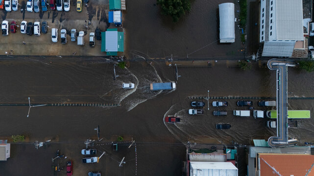 An elevated view of a flooded road with vehicles driving through the water.	