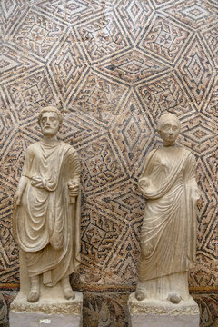 Two Roman Marble Statues in Togas Before a Geometric Mosaic Wall, Algeria