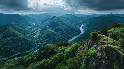 Obraz premium Expansive View of Lush Green Mountain Landscape with River and Dramatic Clouds