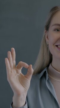 Slow motion portrait of cheerful woman showing OK hand gesture smiling on black studio background. Satisfaction sign and people concept.