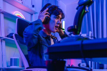Asian man gamer in headset playing flight simulator game with joystick at neon gaming desk © SpaceOak