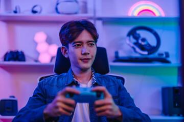 Focused Asian man gamer holding gamepad and playing video game in neon lit gaming room © SpaceOak