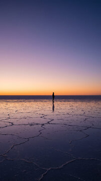 Minimalist Silhouette of Person on Vast Salt Flat Mirror at Purple Sunset