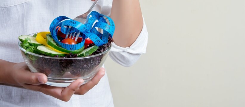 Woman holding bowl of fresh vegetable salad with fork, healthy eating lifestyle concept