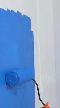 Roller Brush Painting, Worker painting on surface wall Painting apartment, renovating with blue color paint. Leave empty copy space white to write descriptive text beside.	