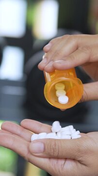 close up woman hand holding a medicine, with pours the pills out of the yellow orange medicine bottle. Stop drug use Taking Medication Caring for the health care medical concept.