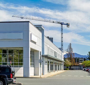 Modern commercial building with parking lot and construction crane