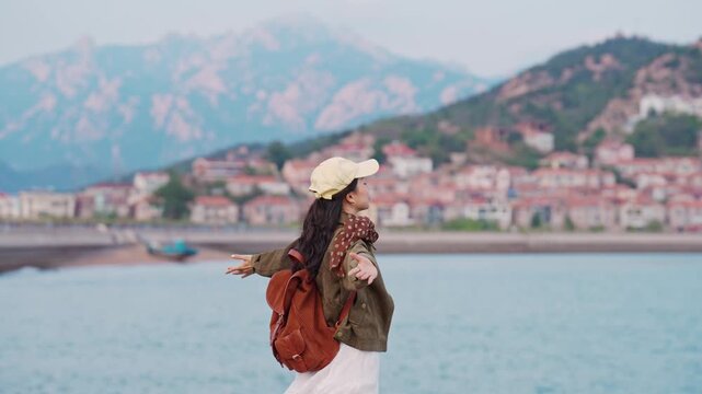 Female tourist relaxing and enjoying the scenic view of the fishing village along the coast at Shazikou in Qingdao