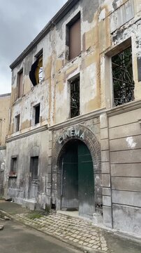 Vertical shot of an abandoned film set facade of a derelict cinema with peeling walls and broken windows on a deserted street 2