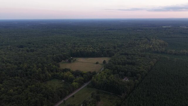 Sold acreage planned for a data center in Louisa County, Virginia, spans a wooded rural setting, with fields and scattered houses in the evening light. Aerial view