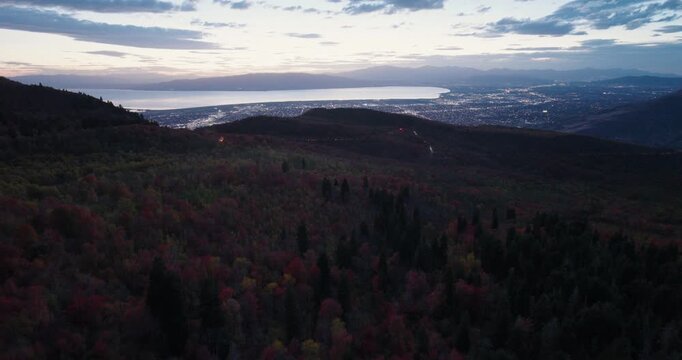 Silhouette Of Autumn Trees On Mountain With View Of Valley And Lake At Dusk - Drone Shot