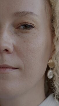 Close-up portrait of beautiful young lady half face looking at camera on black background. Positive emotion and individuality concept.