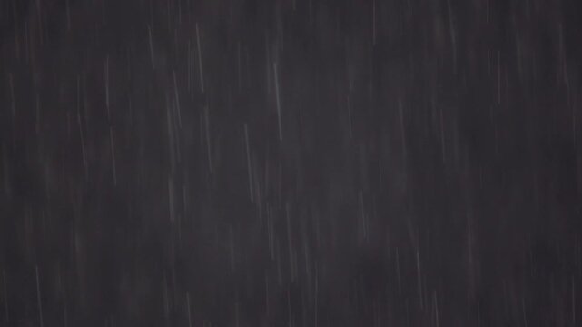 黒い住宅の外壁を背景に美しく降り注ぐ雨粒と雨筋を捉えたスローモーション映像。ピント位置のバリエーション