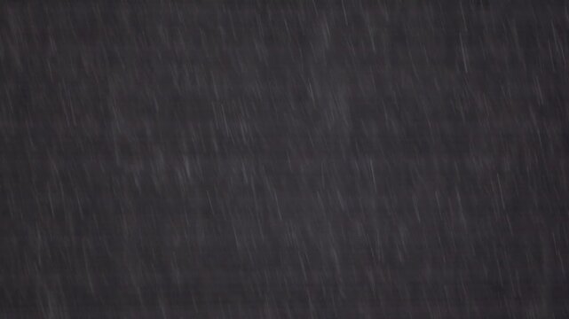 黒い住宅の外壁を背景に美しく降り注ぐ雨粒と雨筋を捉えたスローモーション映像。ピント位置のバリエーション