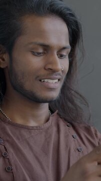 Young Indian man using social media with smartphone texting standing on black studio background. People and modern gadget concept.
