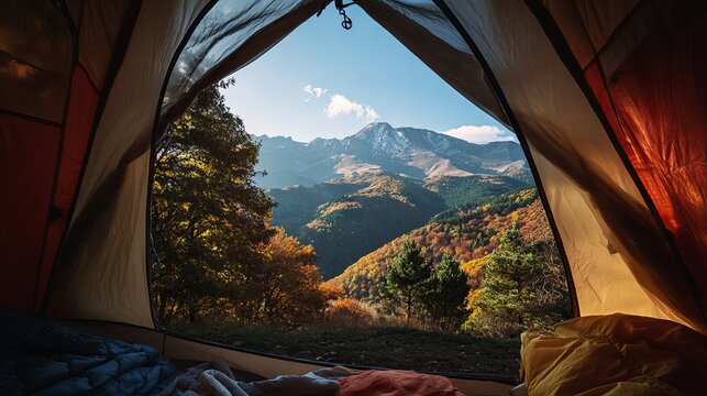Panoramic landscape view looking out from inside a camping tent toward majestic snow capped mountain peaks during autumn