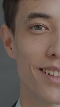Close-up slow motion portrait of happy young man half face looking at camera on black background. People and good mood concept.