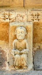 Sculpted Romanesque modillion with seated figure beneath rosettes frieze, 12th-century eaves of San Julian y Santa Basilisa Church in Rebolledo de la Torre, Burgos, Castilla y Leon, Spain © Nandi Estévez