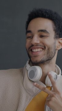 Slow motion of cheerful African American man posing for smartphone camera taking selfie on black studio background. People and photo concept.