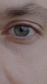 Close-up portrait of young man's eyes looking at camera blinking with no emotion. Face expression and human body part concept.