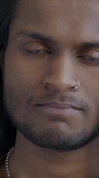 Slow motion portrait of unhappy Indian man pursing lips looking sad on black background. Negative emotion and people concept.