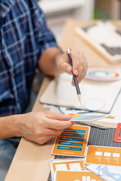 Designer working with color palettes, layout templates, and creative design tools on a desk while planning branding and graphic design projects in a modern office.