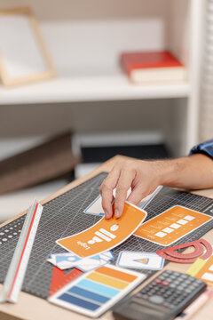 Designer arranging color swatches, layout samples, and branding materials on a creative workspace while planning a visual identity project with notebooks and design tools.