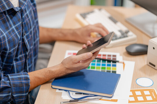 Designer arranging color swatches, layout samples, and branding materials on a creative workspace while planning a visual identity project with notebooks and design tools.