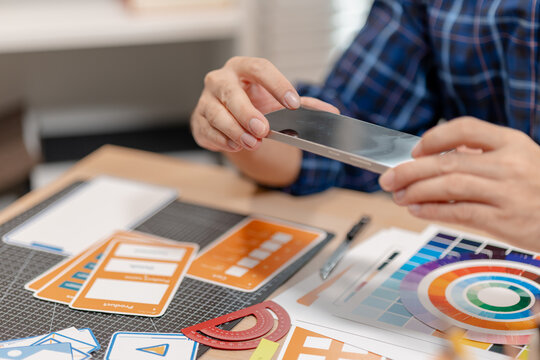 Designer arranging color swatches, layout samples, and branding materials on a creative workspace while planning a visual identity project with notebooks and design tools.