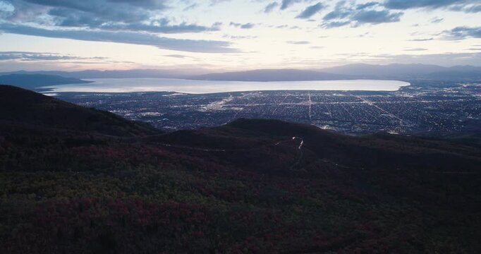 Shadow Covered Autumn Trees In Canyon With View Of City And Lake At Dusk