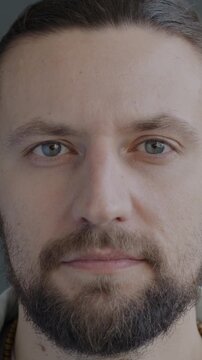 Close-up portrait of serious young man looking at camera with no emotion on black studio background. People and face expression concept.