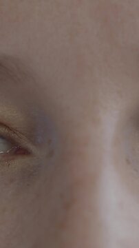 Close-up of female eyes looking at camera blinking while calm lady expressing no emotion. Human body part and face expression concept.