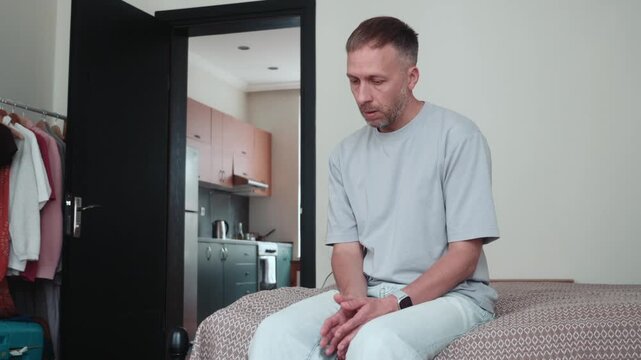 Anxiety and nervous behavior at home as man sits alone, fidgeting, startled by sudden sound, showing hypervigilance, fear and stress.
