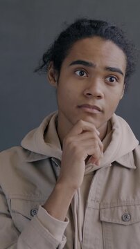 Slow motion portrait of creative African American man thinking then raising finger having idea smiling looking at camera on black color background