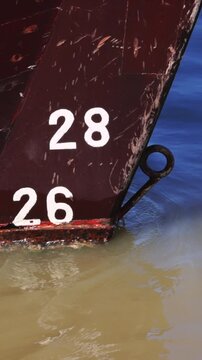 Close-Up Footage of Ship Draft Marks on Weathered Red Hull at Waterline